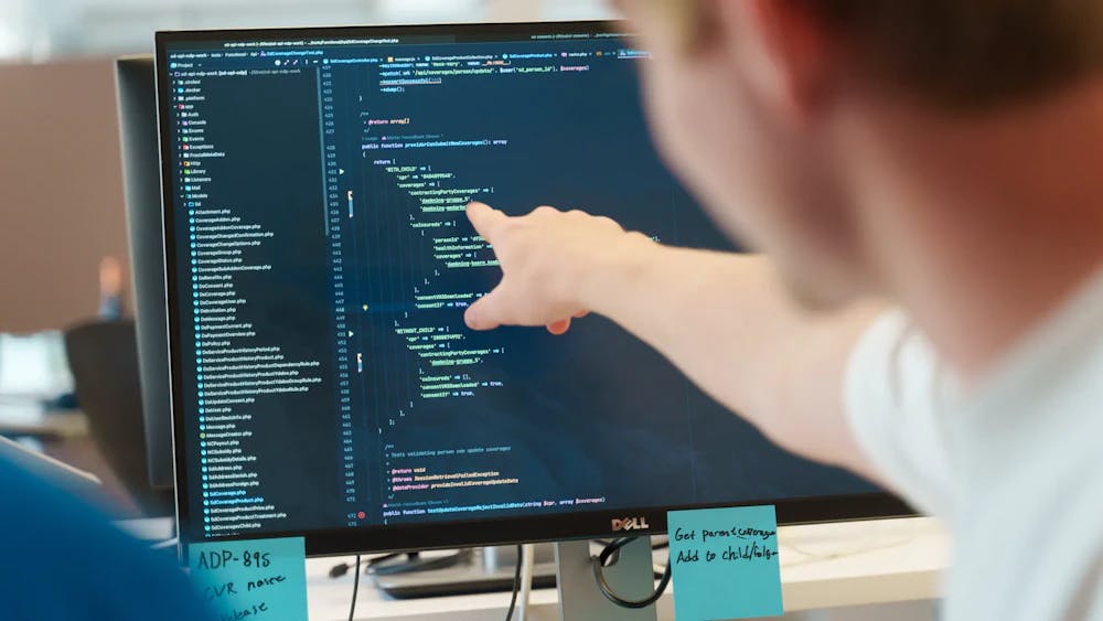 a person points to code displayed on their computer screen