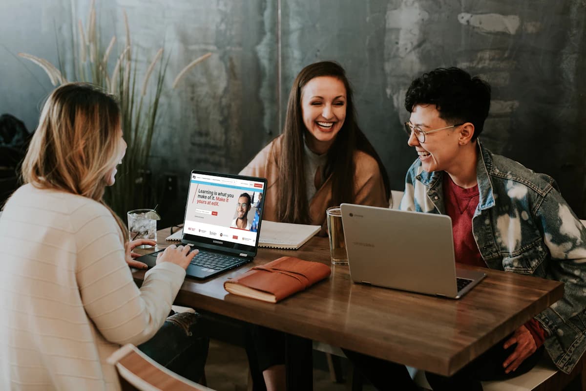 three people sitting at a table, their laptops are open to the edx website