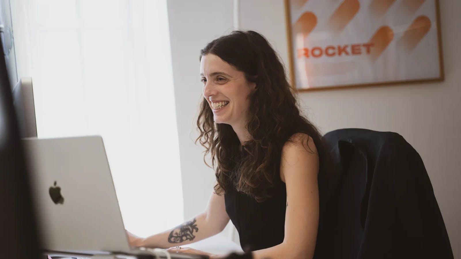 woman laughing next to a computer