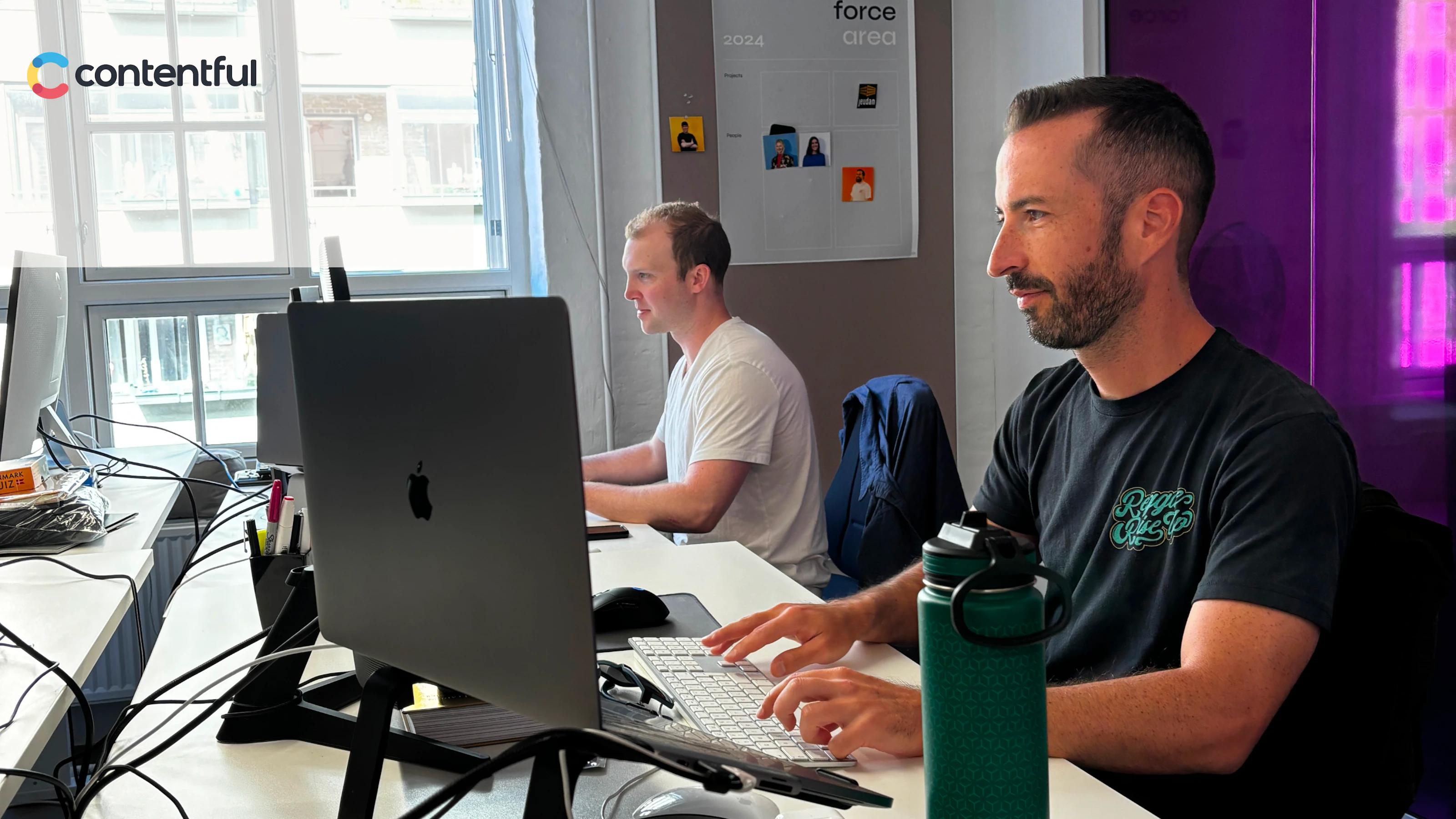 Two Adapt USA employees working with Contentful logo