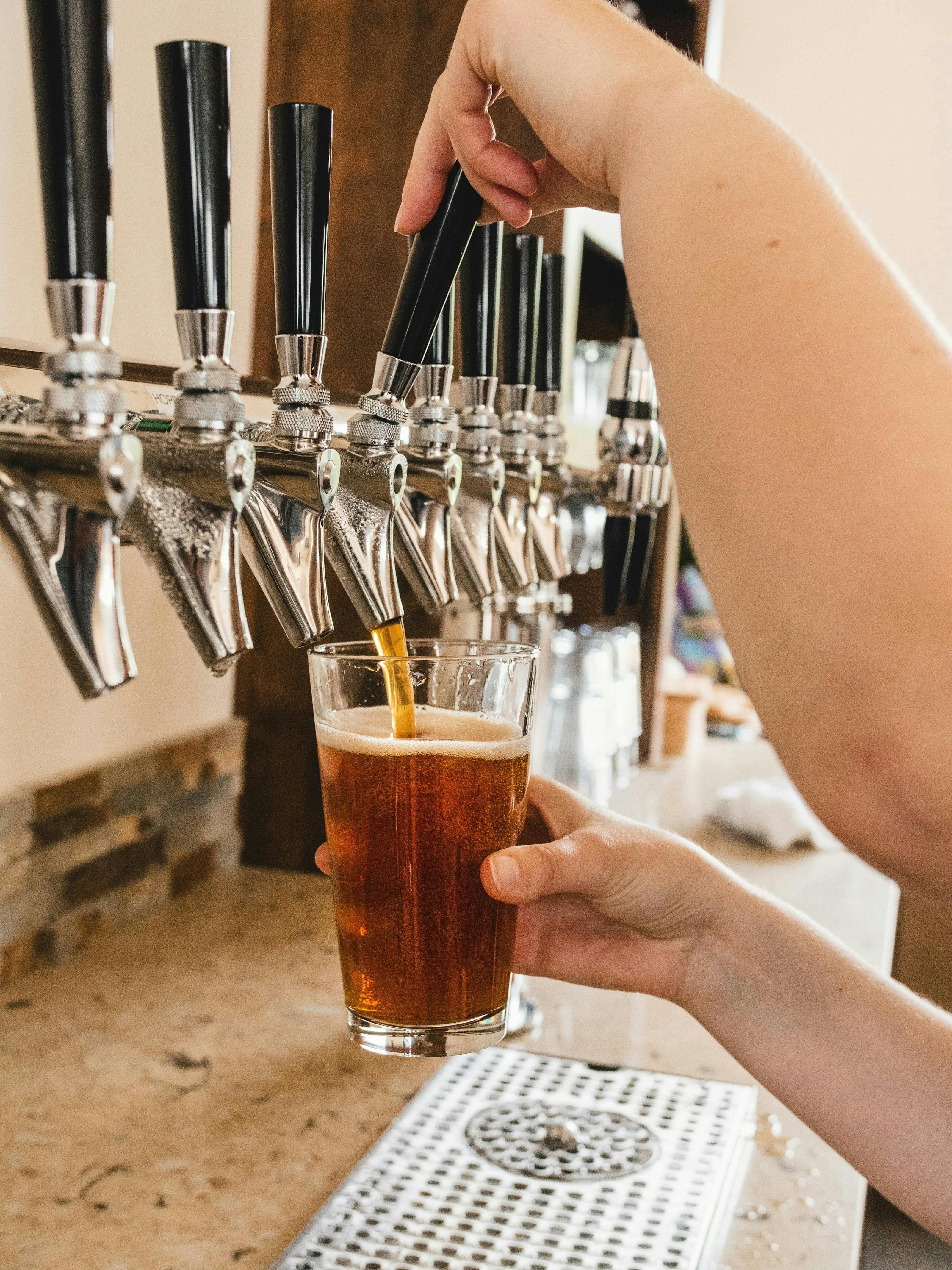 a person pours an amber-colored beer from a draft