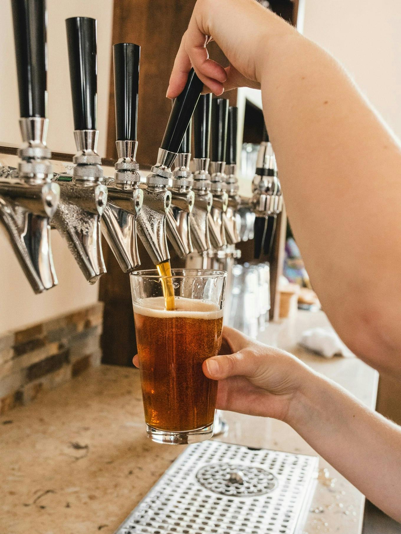 a person pours an amber-colored beer from a draft