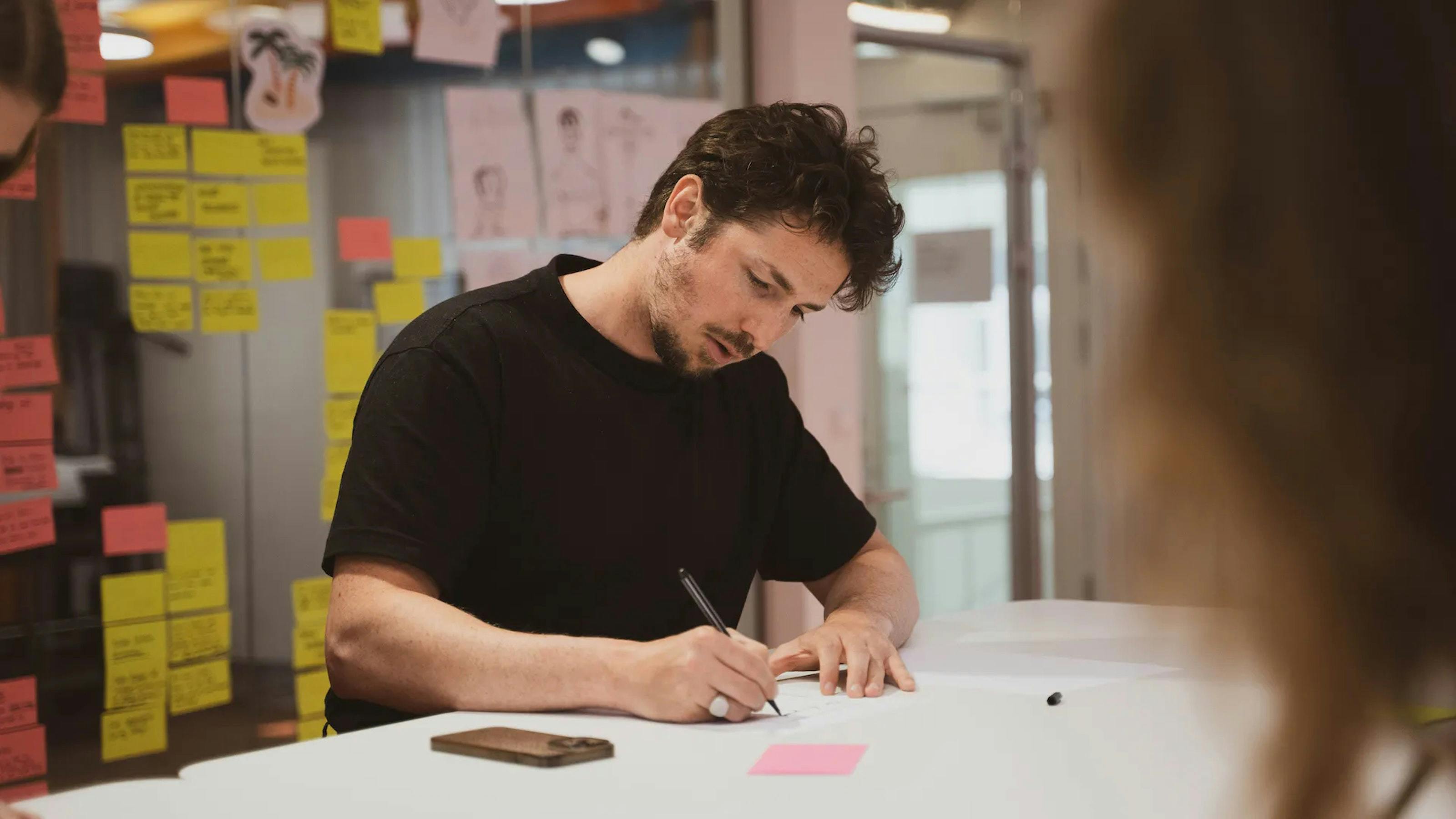 man writing on a sticky post it note